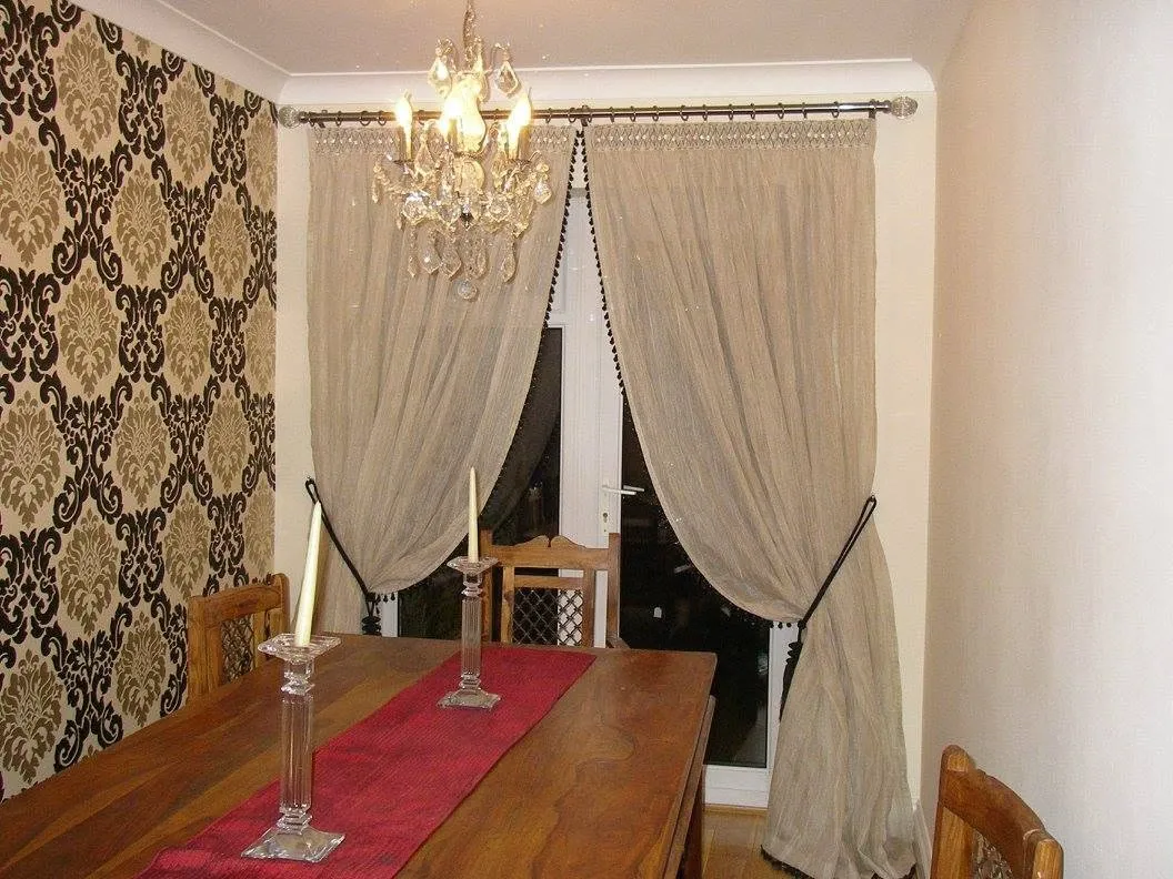 Cream dining-room curtains beneath a chandelier