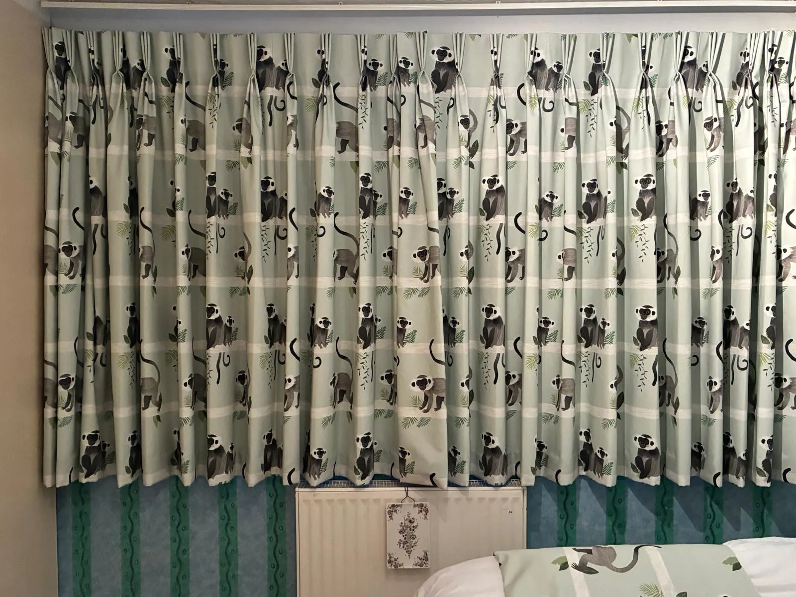 Wall-to-wall handmade pinch-pleat curtains in a monkey-print fabric