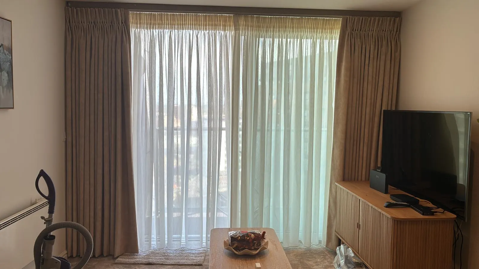 Taupe curtains and white sheers across a living-room window wall